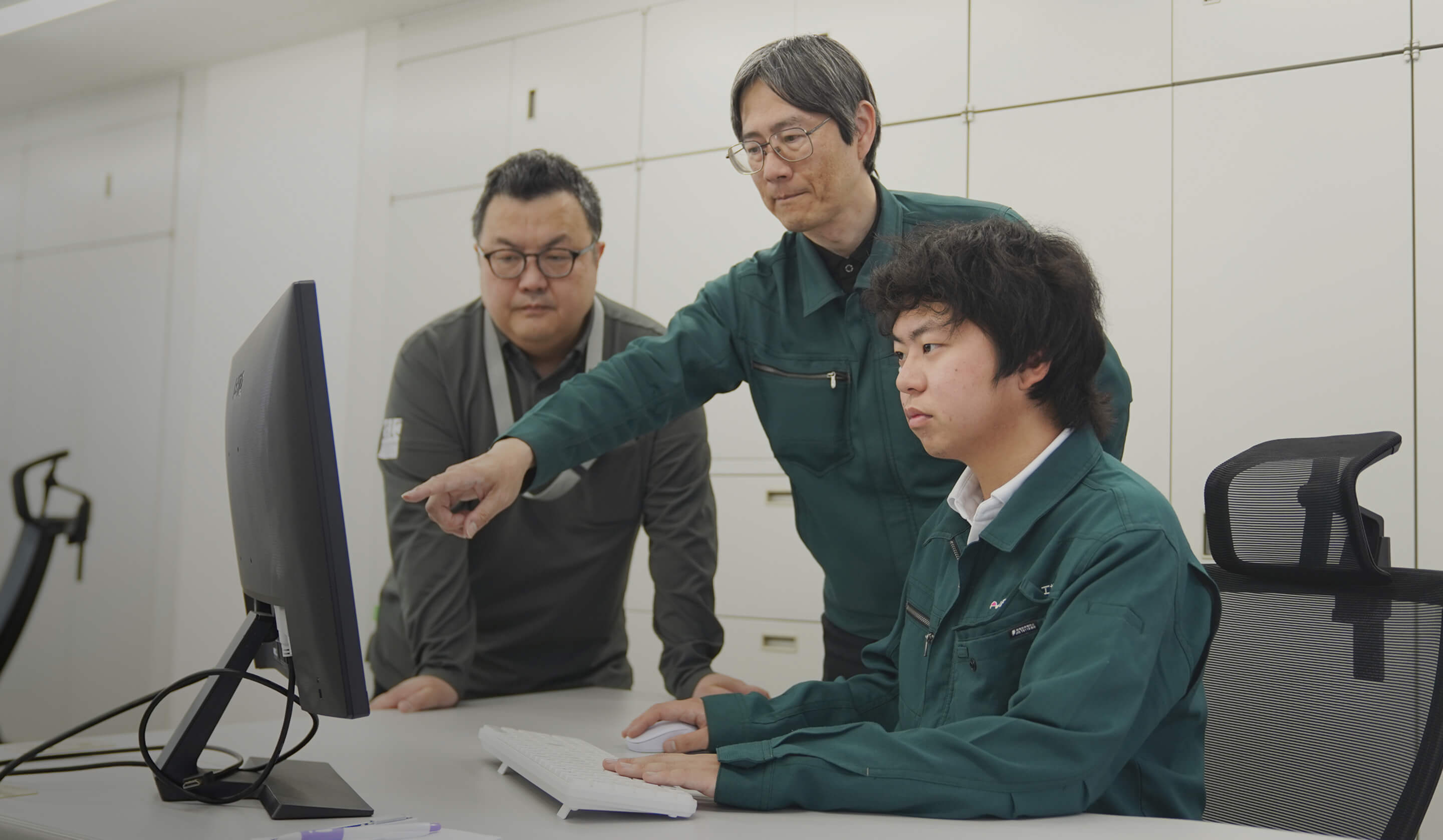 モニターを囲んで話をする社員たち